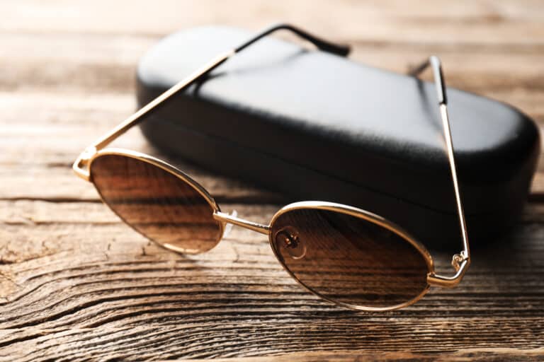 Stylish sunglasses and case on wooden table, closeup